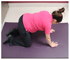 Pregnant woman on her hands and knees on the floor.