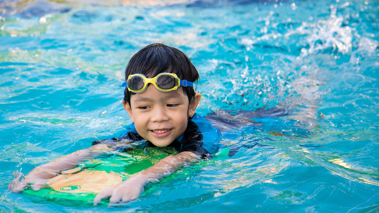 child in pool swimming with kickboard