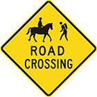 yellow diamond-shaped sign with black icon of a person riding a horse and a person hiking, as well as text, road crossing