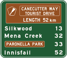 green sign with white text list of locations and distances with brown panels showing tourist drive info