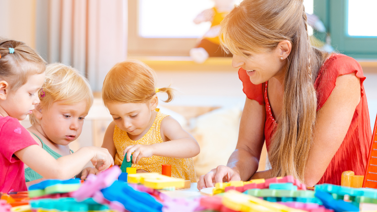 Children playing with block toys with an adult watching and helping