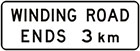 white sign with black text, winding road ends 3km