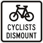 white sign with black icon of a bicycle and the words cyclists dismount