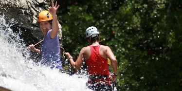 Two women rock climbing in a waterfall.