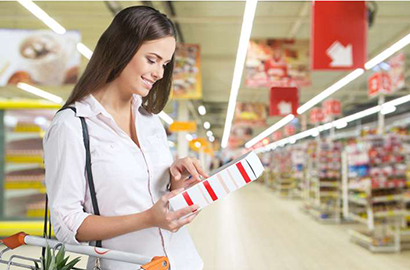 Woman reading food label in supermarket