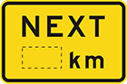 yellow sign with the word next in black, and space for a distance in km or m