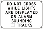 white sign with black text, do not cross while lights are displayed or alarm sounding, number of tracks