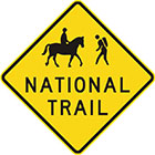 yellow diamond-shaped sign with black icon of a person riding a horse and a person hiking, as well as text, national trail