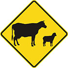 yellow diamond-shaped sign with black icons of a cow and a sheep