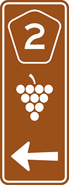 brown sign with pentagonal route number badge, grapes icon and an arrow