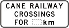 white sign with black text, cane railway crossings for number of km