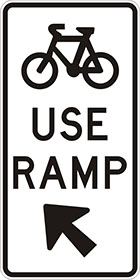 white sign with black icon of a bicycle, the words use ramp, and an arrow