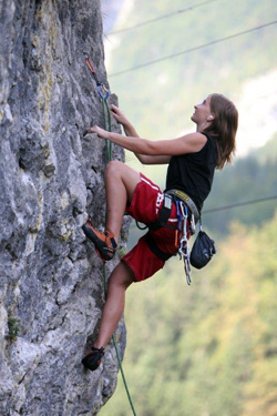 Girl in a hard hat climbing a rope.