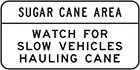 white sign with black text, sugar cane area. Watch for slow vehicles hauling cane