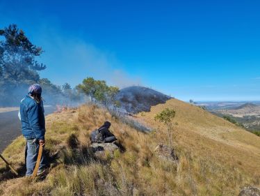 Rangers on grassy hill watching cool fire.