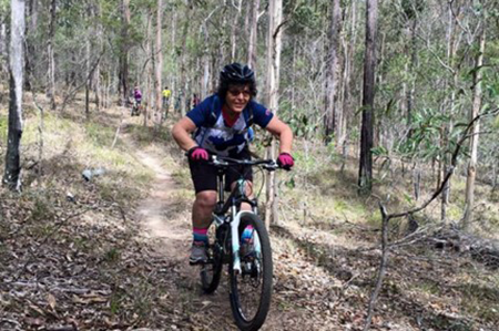 A person mountain biking in the bush.