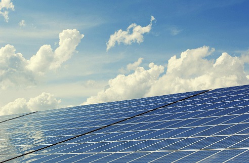 A set of solar panels below a cloudy blue sky